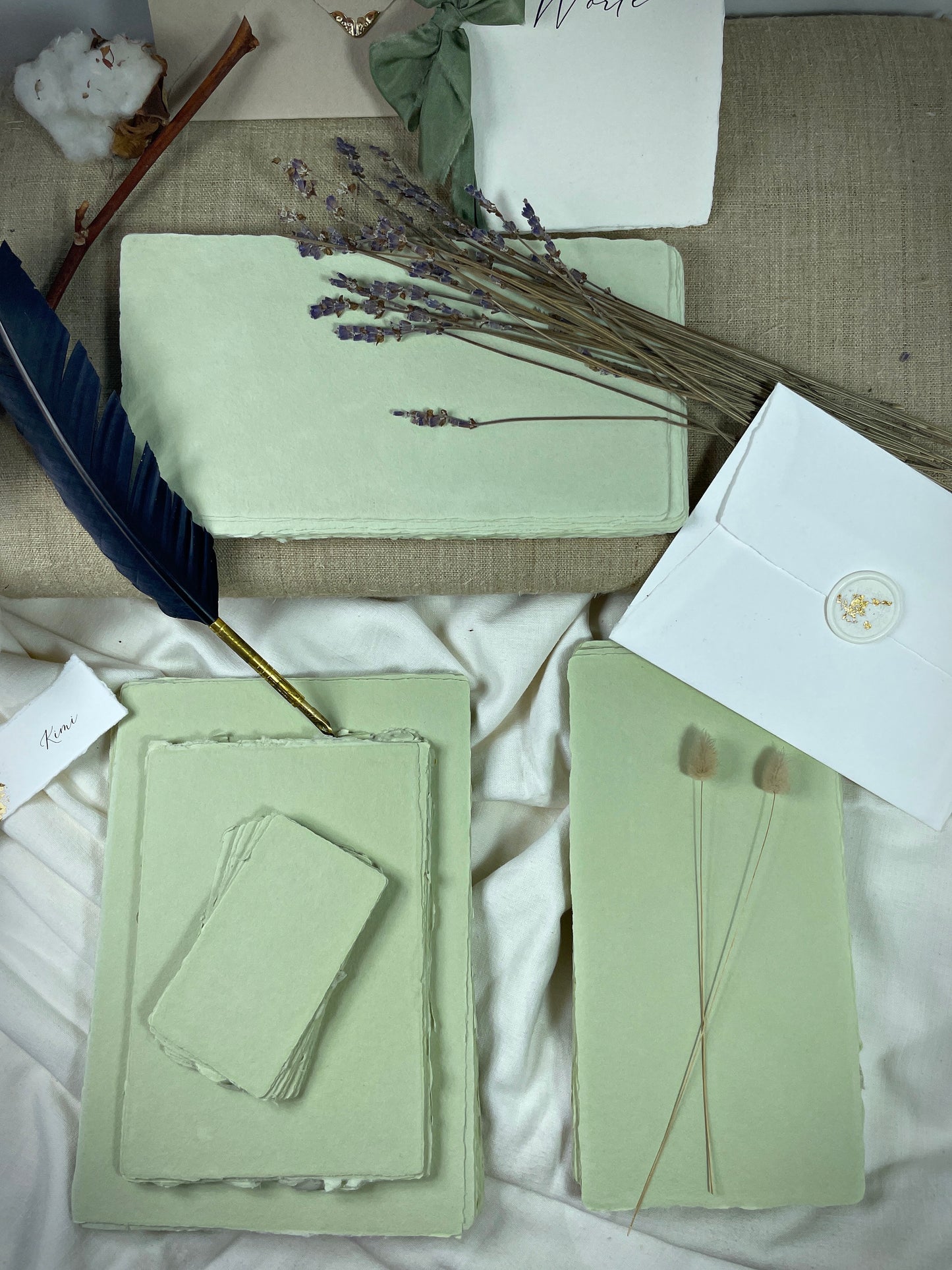 dekoratives Arrangement von grünem Büttenpapier mit Schreibfeder