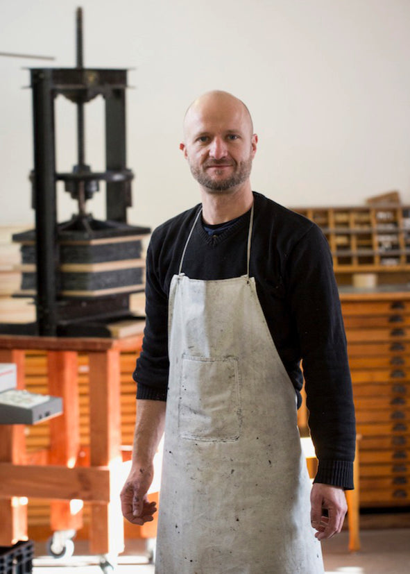 Papiermacher Matthias Schwethelm in seiner Werkstatt mit Papierpressen im Hintergrund